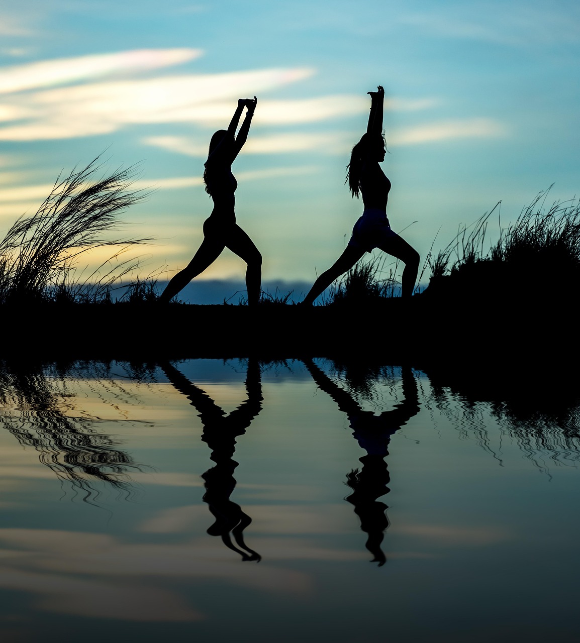 Two women doing yoga next to lake