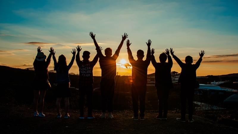 People with their hands raised at sunset